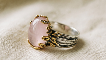 Rose quartz silver ring with organic gold prongs resting on aged linen, Goldlip Jewelry