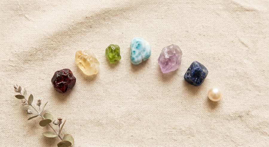 Gemstones arranged from warm to cool tones on linen cloth